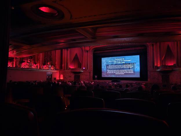 A room with a large screen and red lights

AI-generated content may be incorrect.