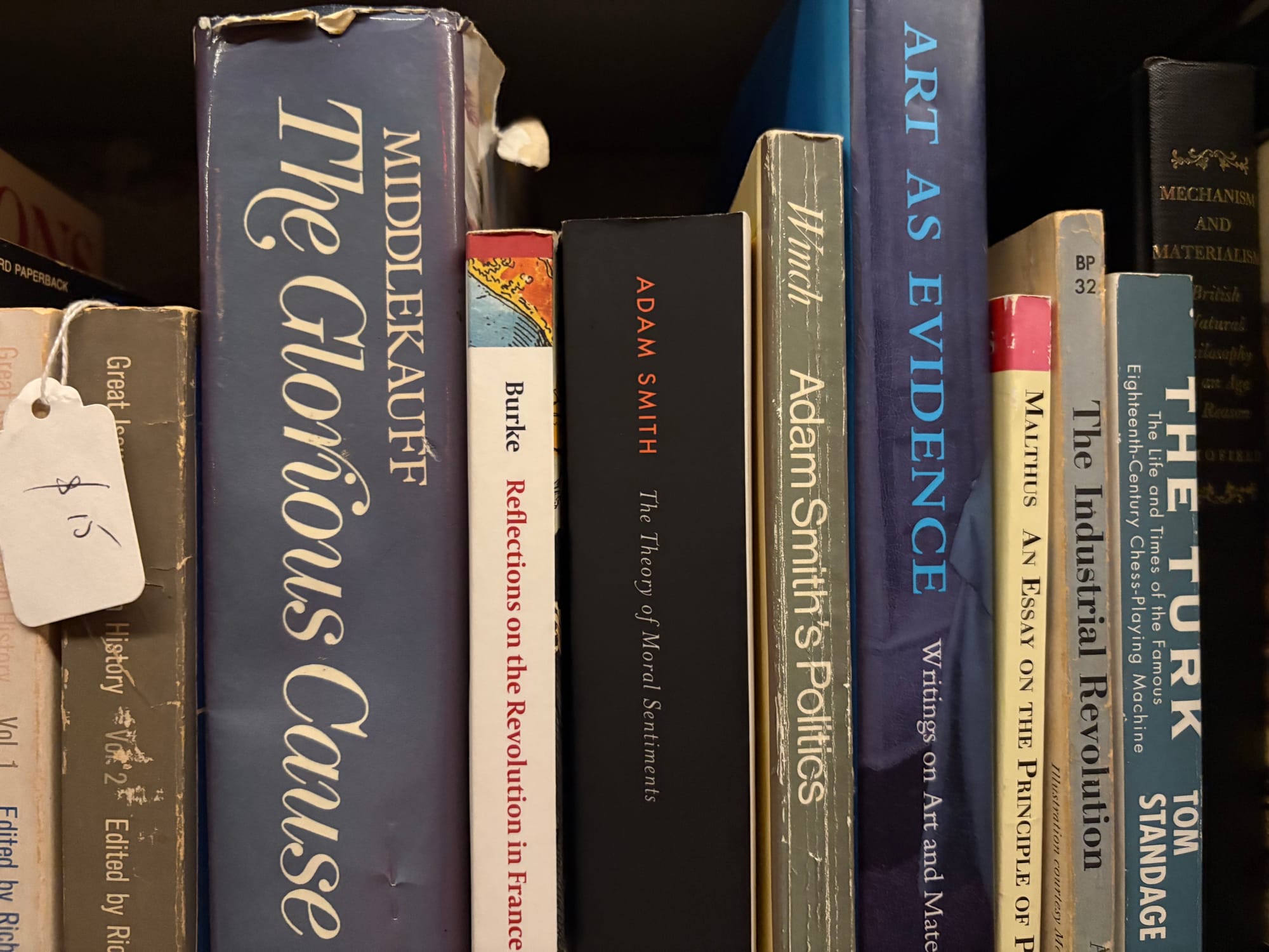 A shelf of books, including a couple Adam Smith titles, as well as a Malthus, a Burke, and some other bullshit.