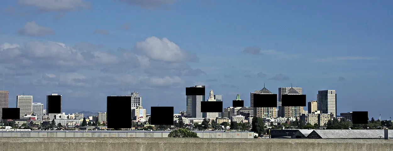 A photo of the Oakland skyline, with black boxes over buildings a la the redacted photos in the Epstein files.